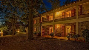 A two-story stone building with a balcony, large windows, and a tree in the foreground. - Lovely apartment for 6 guests with pool, WIFI, veranda and panoramic view, close to San Gimignano (Montaione)