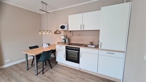 Una cocina compacta con una mesa de comedor de madera, horno empotrado y muebles de cocina blancos.