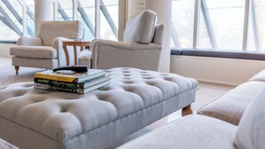 Een moderne woonkamer met een geruite poef, een stapel boeken en een afstandsbediening erop.