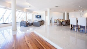 Een ruime woonkamer met een modern design, met een grote bank, een eettafel met stoelen en een decoratieve plantenstelling.