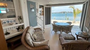 Ein Zimmer mit einem Korbsessel, einem Esstisch und Meerblick.