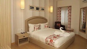 A hotel room with a large bed, bedside tables, a mirror, and wall-mounted lights. - Hotel Mayvillas Luxury Boutique Stay (Dehradun)