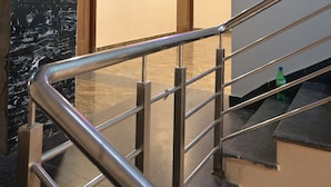 A modern hotel lobby with a marble wall, a staircase with metal railings, and a sign indicating the dining hall location. - Hotel Keptown Lite (Jaipur)