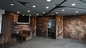 A modern interior with a stone wall, a wooden door, a sofa, and a table. - Hotel Keptown Lite (Jaipur)