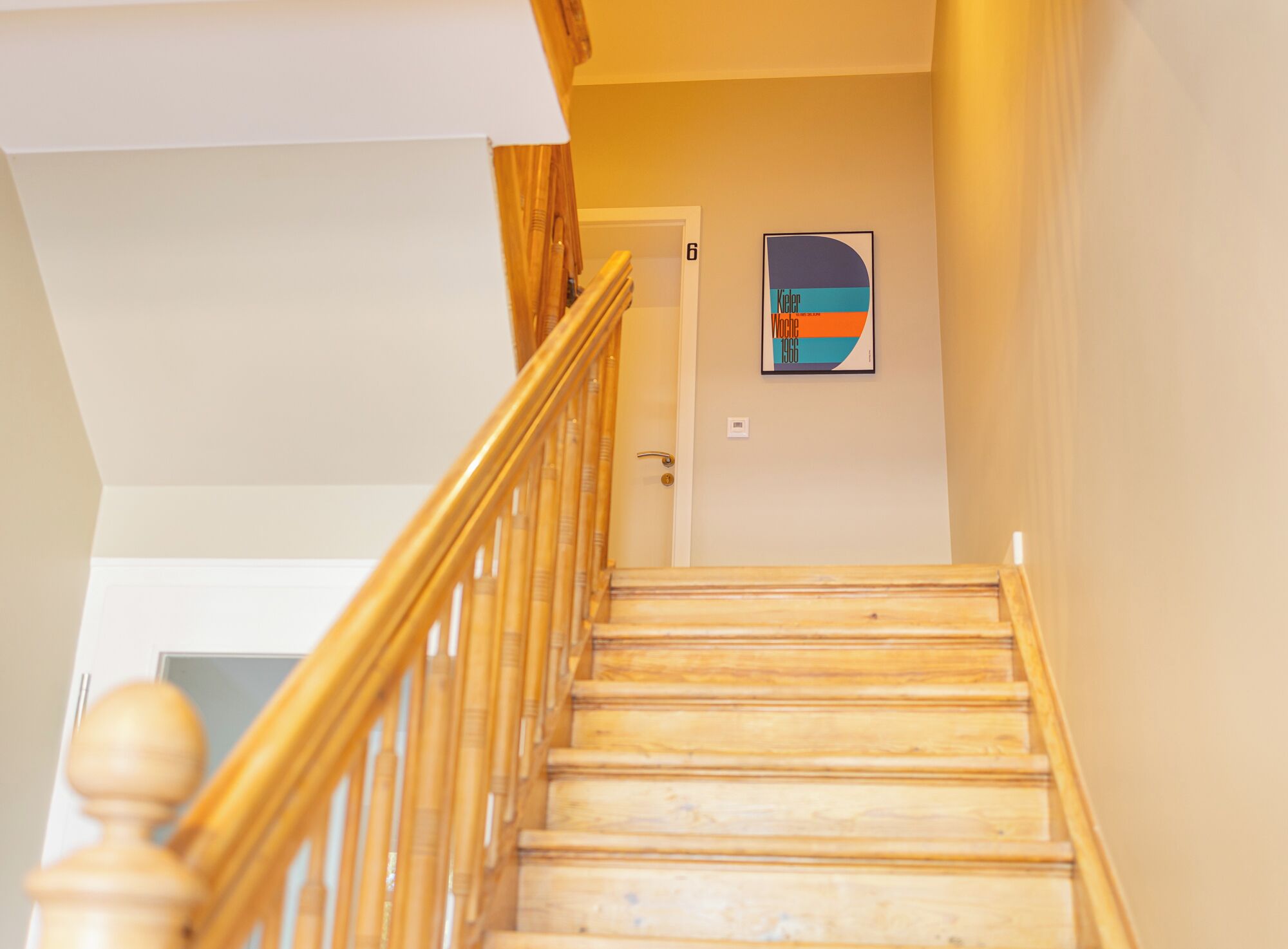 Un escalier en bois, doté d’une rampe, mène à une porte portant le numéro 6.