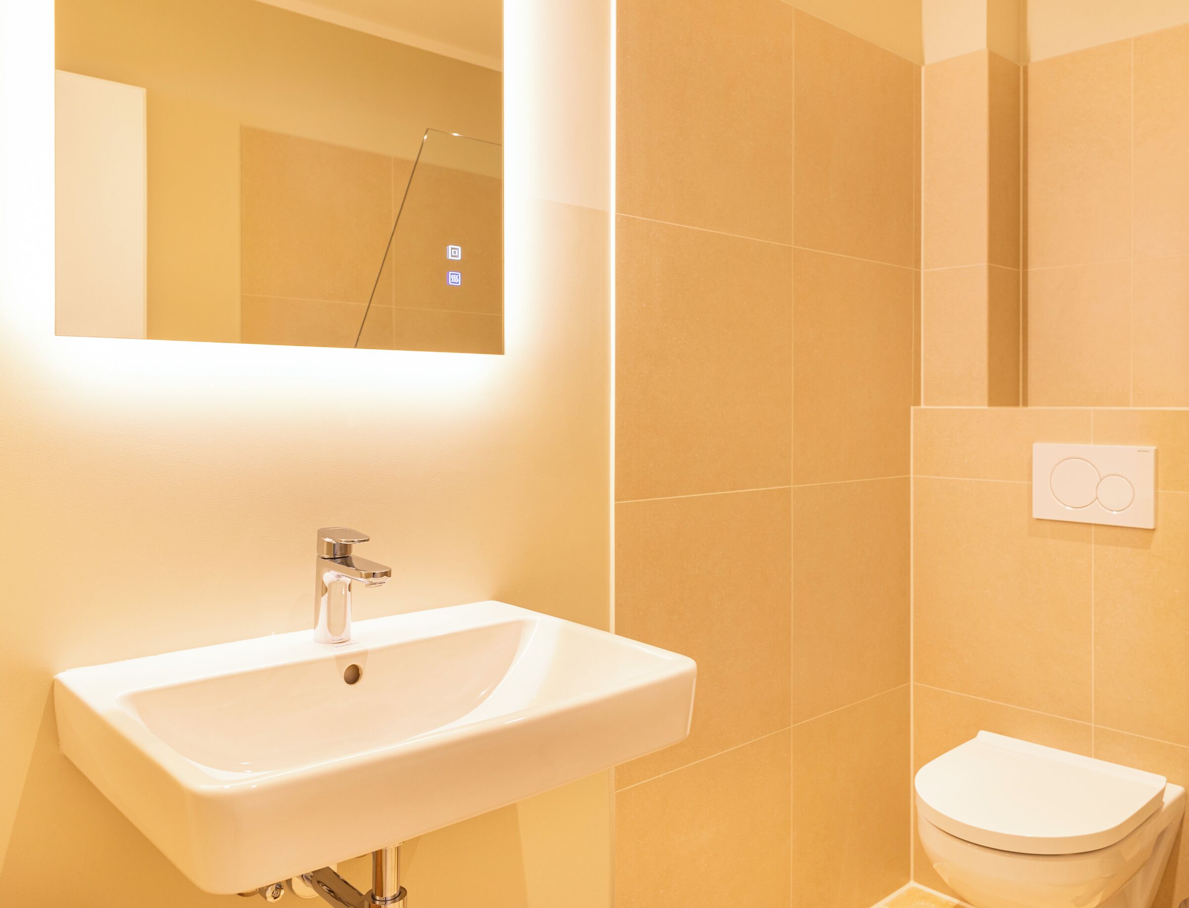 Un baño con lavamanos blanco, espejo y retrete.