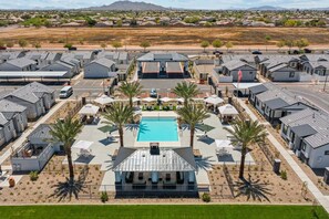 Zona residencial con casas modernas, piscina central y palmeras.