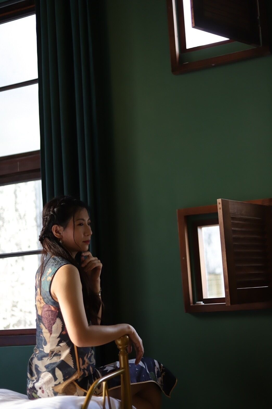 A room with a bed, a window with curtains, and a wooden chair.