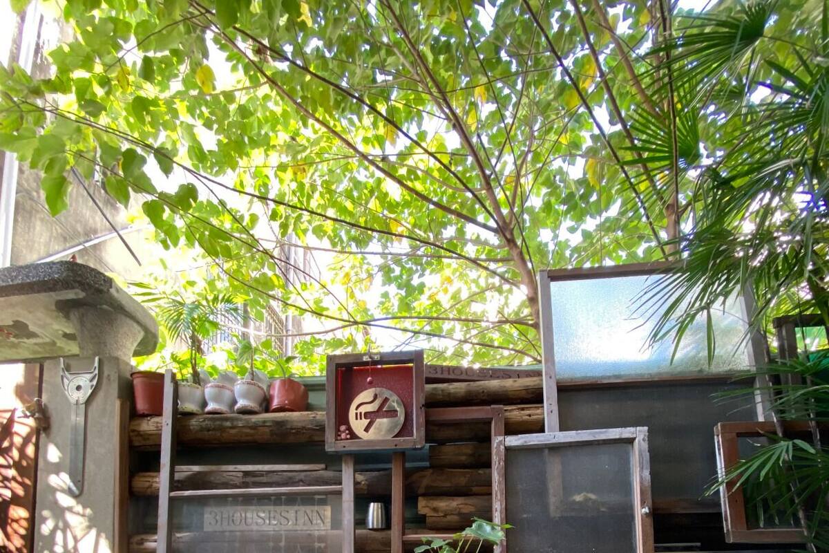 A rustic outdoor seating area with two metal chairs and a small table, surrounded by wooden shelves and potted plants.
