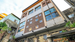 Un immeuble à plusieurs étages dont les façades sont faites d’un mélange de briques et de béton, avec de nombreuses fenêtres et des caméras de surveillance bien visibles.