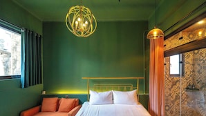 Une pièce comprenant un lit, un canapé, une table et un mur orné d’un motif.