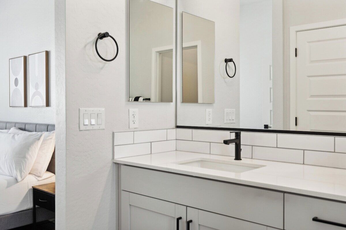 A modern bathroom with a white vanity, a large mirror, and a door.