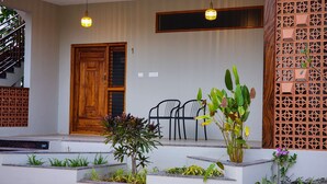 A building with a wooden door, a staircase, and a seating area with chairs. - Poojaris Niranthara Kabini (Mysore)