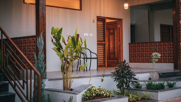 A hotel entrance with a wooden door, a staircase, and potted plants. - Poojaris Niranthara Kabini (Mysore)