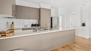 Una cocina moderna con una isla grande, armarios blancos y un refrigerador de acero inoxidable.