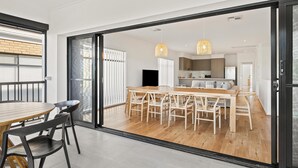 Una cocina moderna con zona de comedor, ventanas amplias y puerta corrediza de vidrio que da a un balcón.