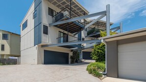Un immeuble résidentiel moderne à plusieurs étages, doté d’un garage, d’un escalier et d’un balcon.
