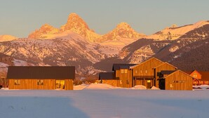 Un complejo de edificios de madera con un paisaje nevado y montañas al fondo.