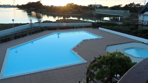 A swimming pool with a view of a lake and a bridge in the background. - Appartement de Charme Dans Résidence Sécurisée Avec Balcon et Piscine Chauffée (Guérande)