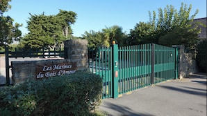 A gated entrance with a sign reading "Les Marines du Bois d'Amour" and a stone wall. - Appartement de Charme Dans Résidence Sécurisée Avec Balcon et Piscine Chauffée (Guérande)