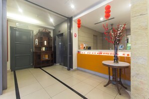 A hotel lobby with a reception desk, a wooden cabinet, and a door labeled "KELUAR".
