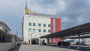 Een hotel met een groot bord, een overdekte parkeerplaats en een heldere lucht.