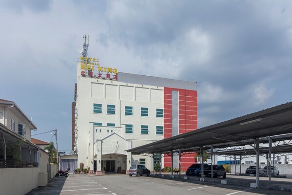 A hotel with a large sign, a covered parking area, and a clear sky.