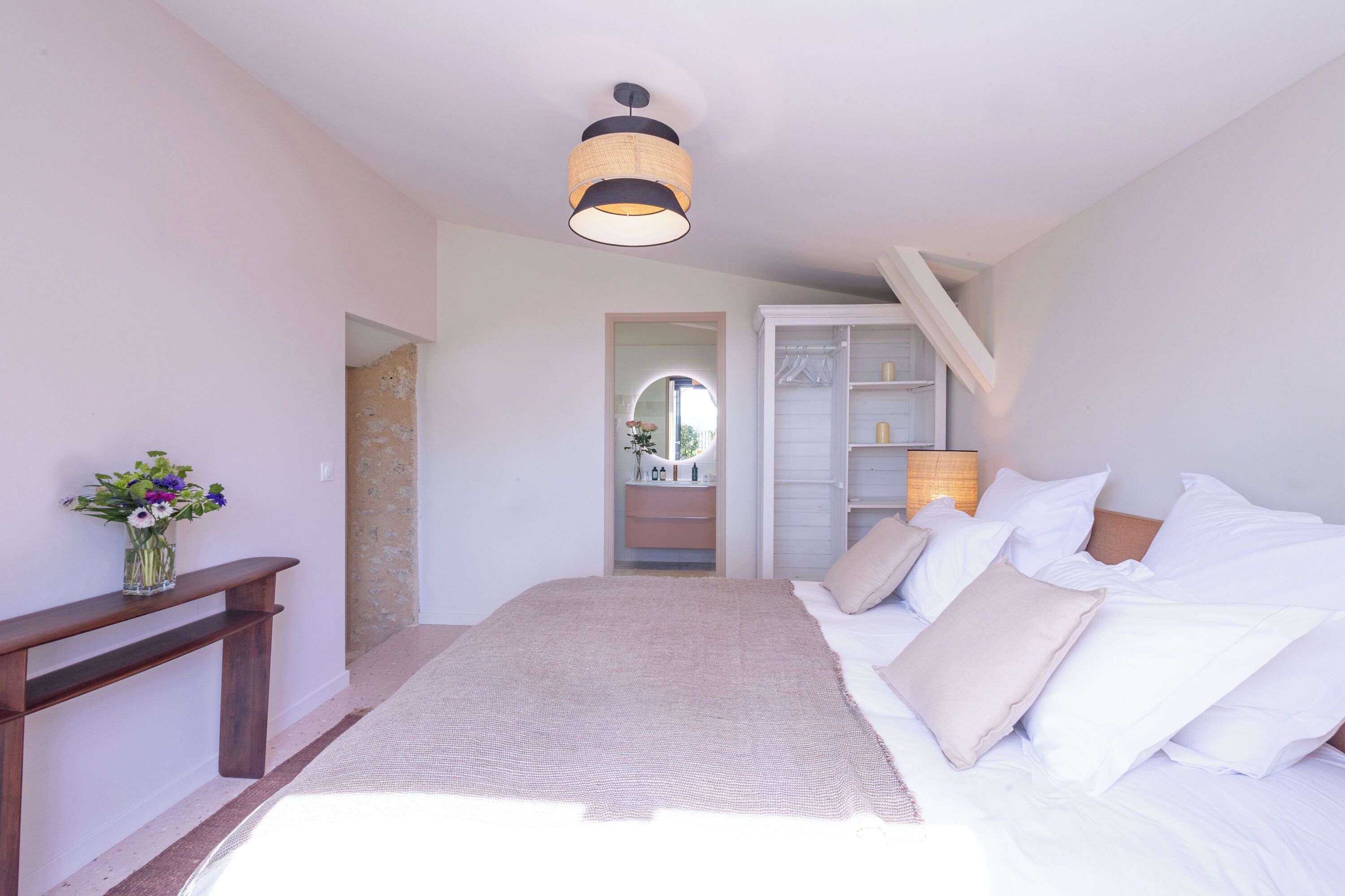 Une chambre à coucher avec un lit, une table de chevet, une lampe et un miroir.