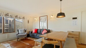 A modern living room with a sofa, chairs, a wooden dining table, and a cowhide rug. - Shamrock 1 - Mt Hotham (Hotham Heights)