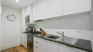 A modern kitchen with white cabinets, stainless steel appliances, a microwave, a toaster, and a sink. - Shamrock 1 - Mt Hotham (Hotham Heights)