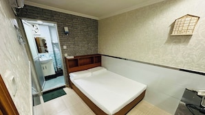 A bedroom with a wooden bed, a small bedside table, a mirror, and a bathroom visible through an open door. - Tai Tung Hostel (Kowloon)