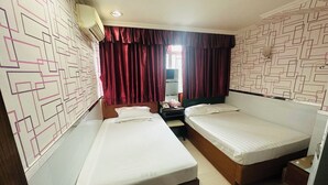 A hotel room with two single beds, a small desk with a telephone, and a mirror. - Tai Tung Hostel (Kowloon)