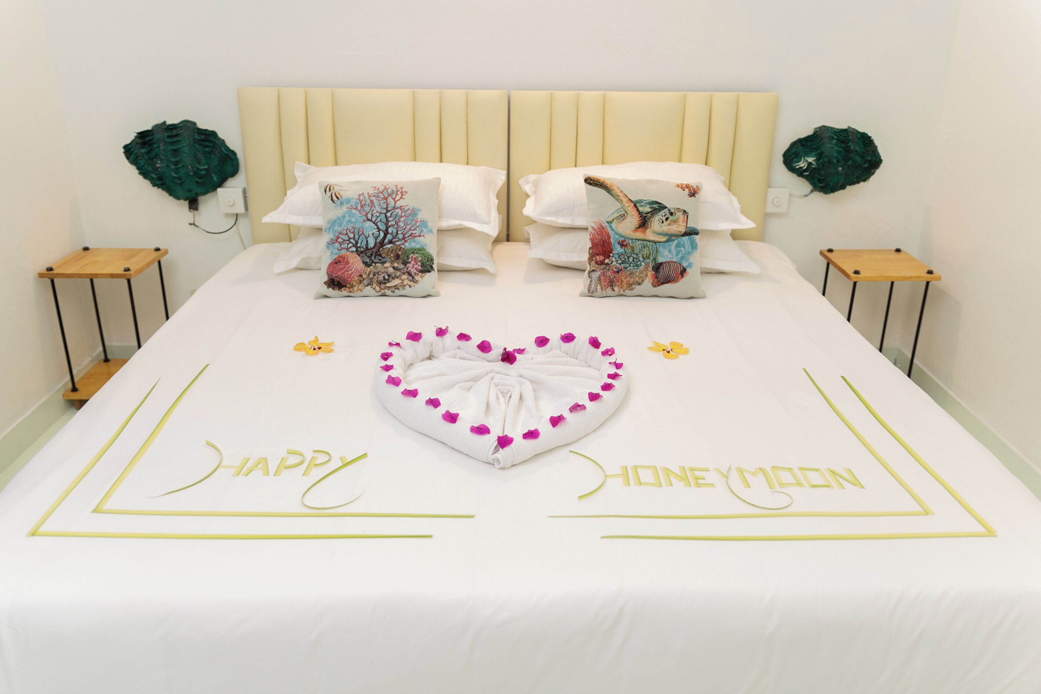 A neatly made bed with a heart-shaped towel and the words "HAPPY HONEYMOON" on the bedspread.