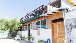 A building with a wooden balcony, a signboard, and a door. - Fasdheythere Inn (Kendhoo)