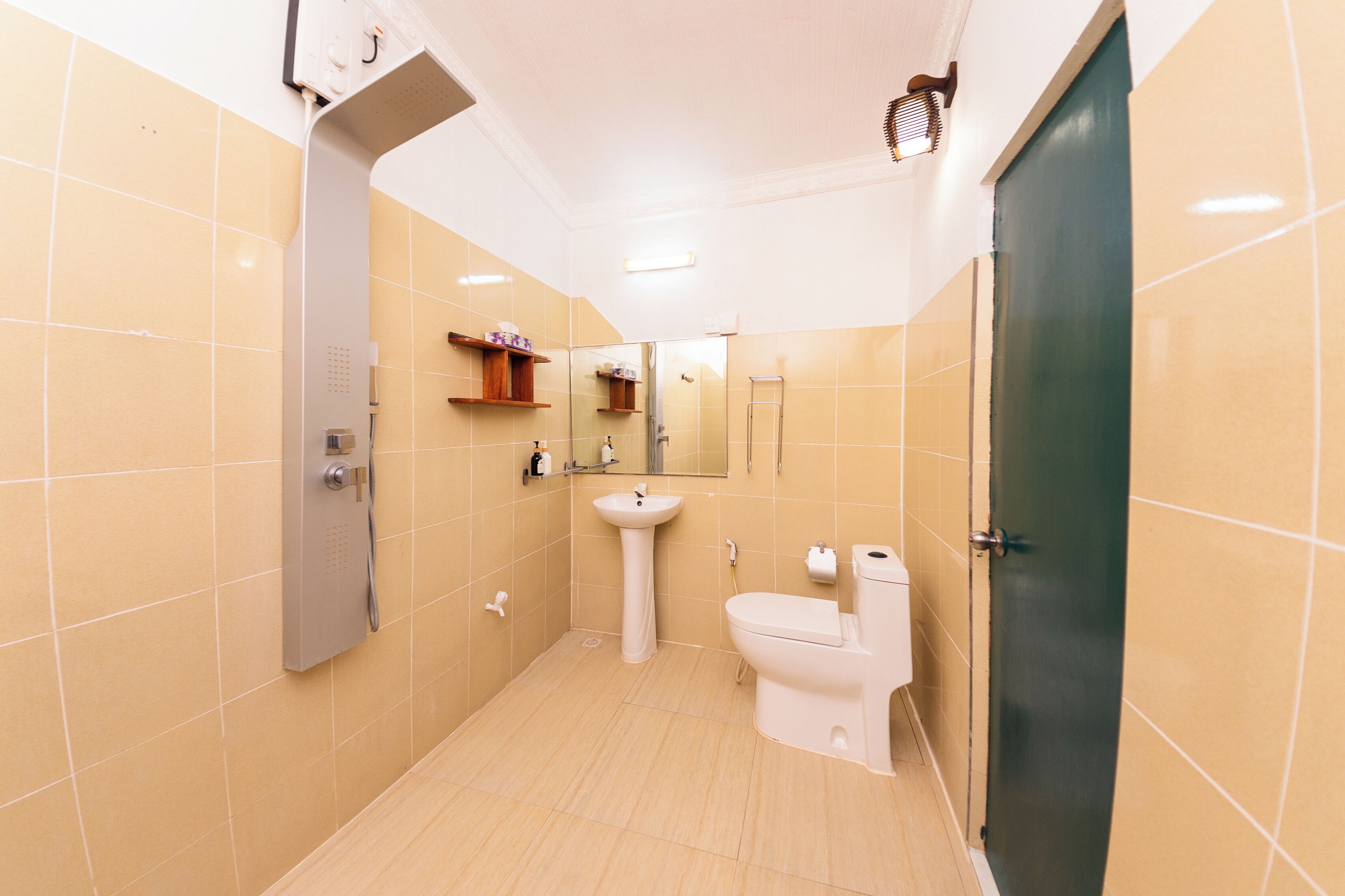 A bathroom with beige tiles, a pedestal sink, a toilet, and a shower area.