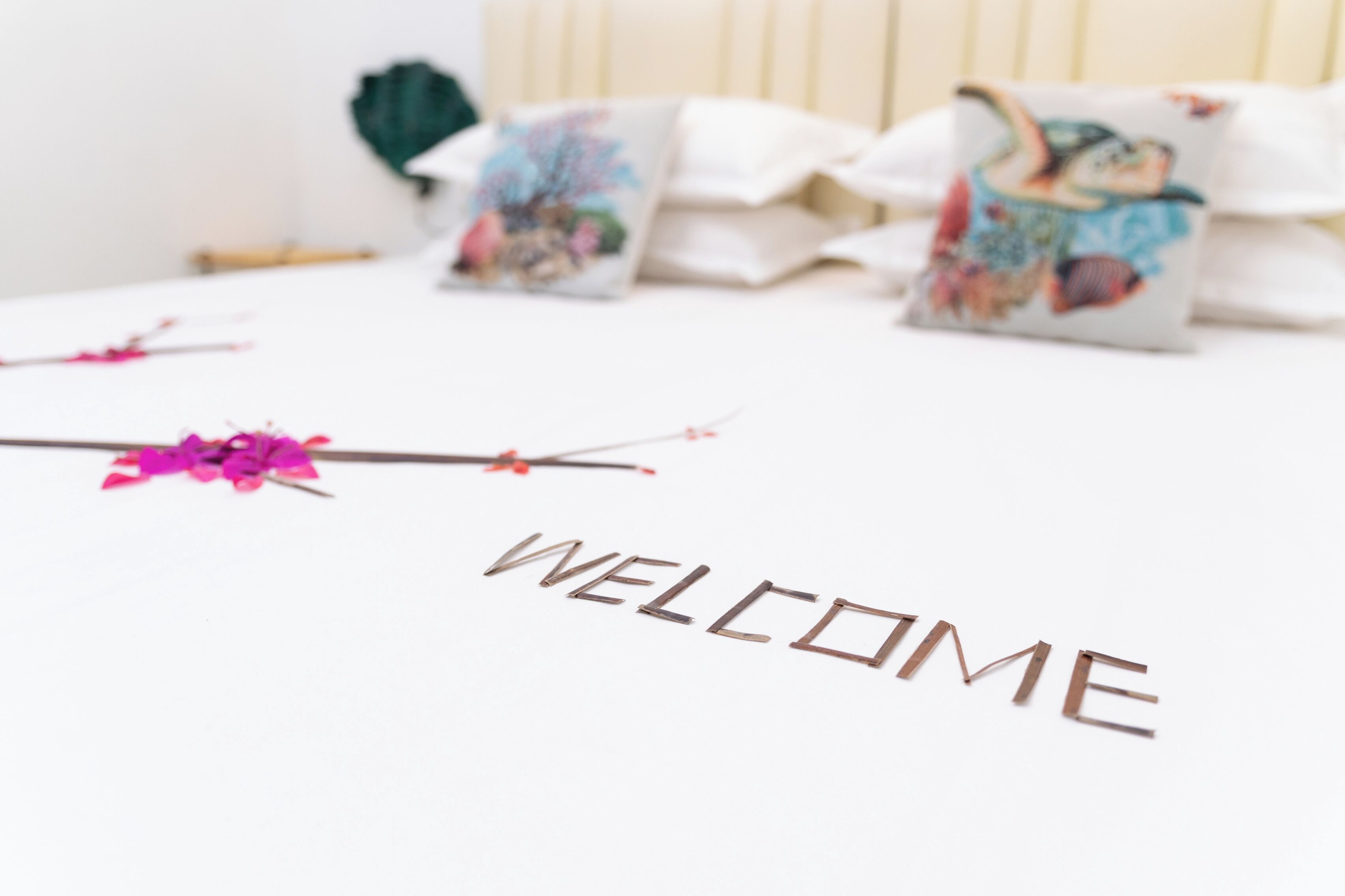 A bed with a 'WELCOME' sign and decorative pillows.