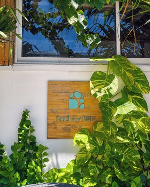 Un letrero de madera con texto, rodeado de plantas verdes exuberantes.