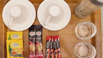 Una bandeja con dos tazas blancas, dos vasos, un salero y sobres de Nescafé y té Super Lemon.
