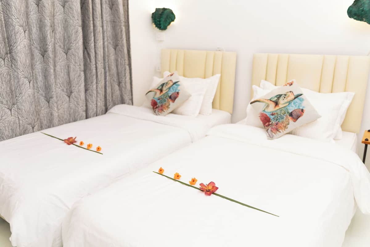 A hotel room with two beds, each with a white bedspread and decorative pillows.