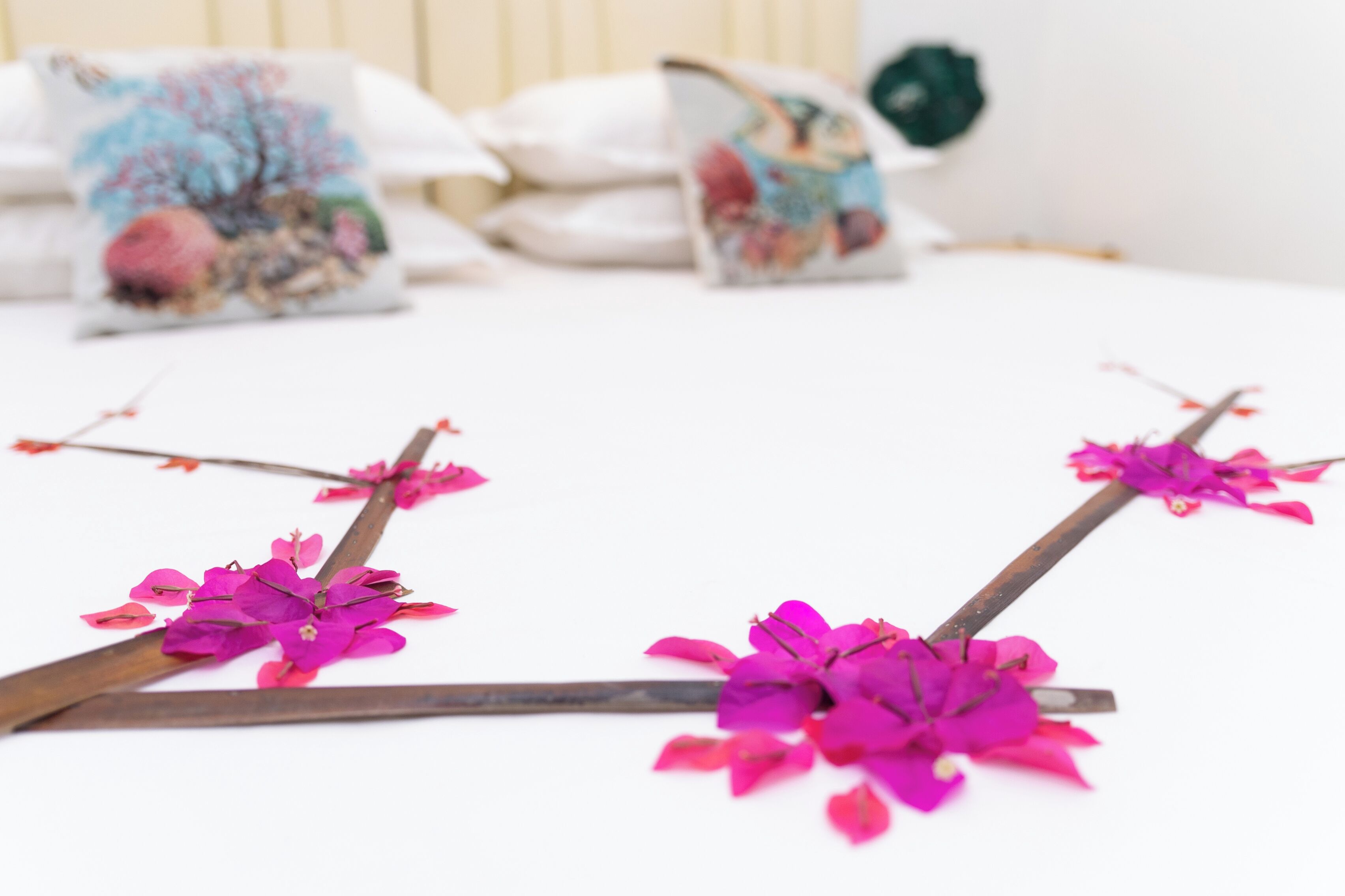 Cama com almofadas decorativas e um arranjo floral.