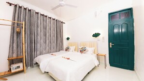 A bedroom with a bed, curtains, a wooden ladder, a green door, and a ceiling fan. - Fasdheythere Inn (Kendhoo)
