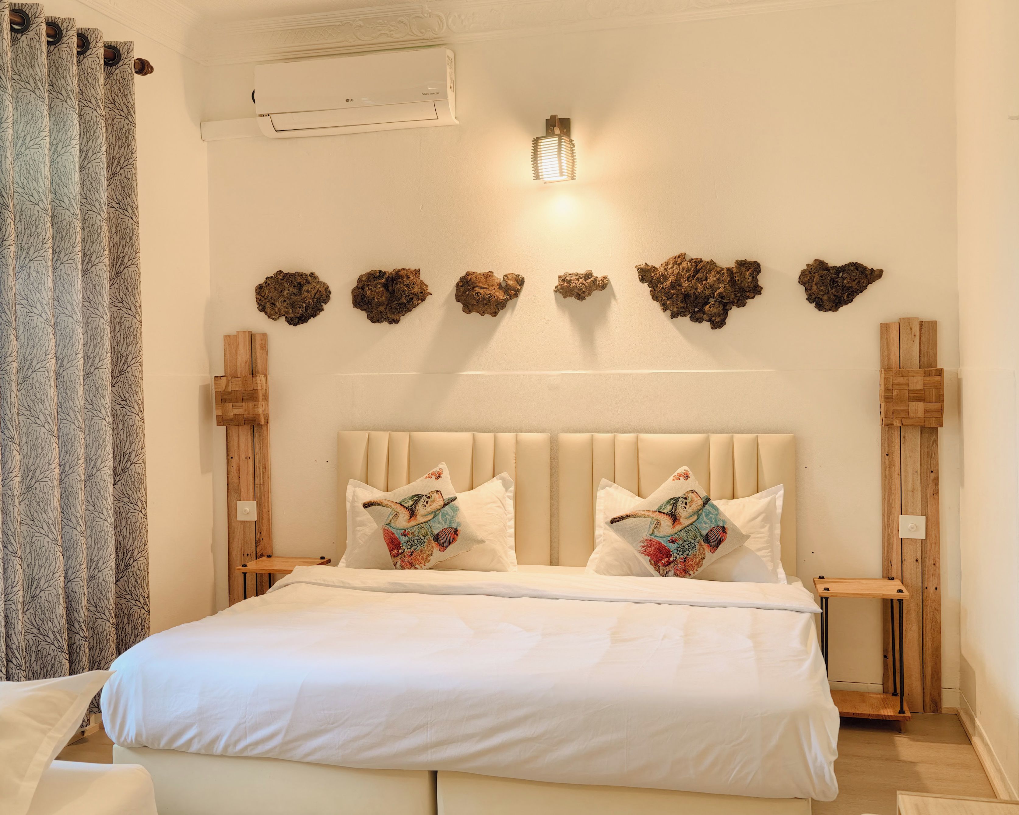 A bedroom with a bed, two nightstands, a wall-mounted light fixture, and decorative wall art.