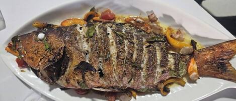 A grilled fish dish on a white plate.