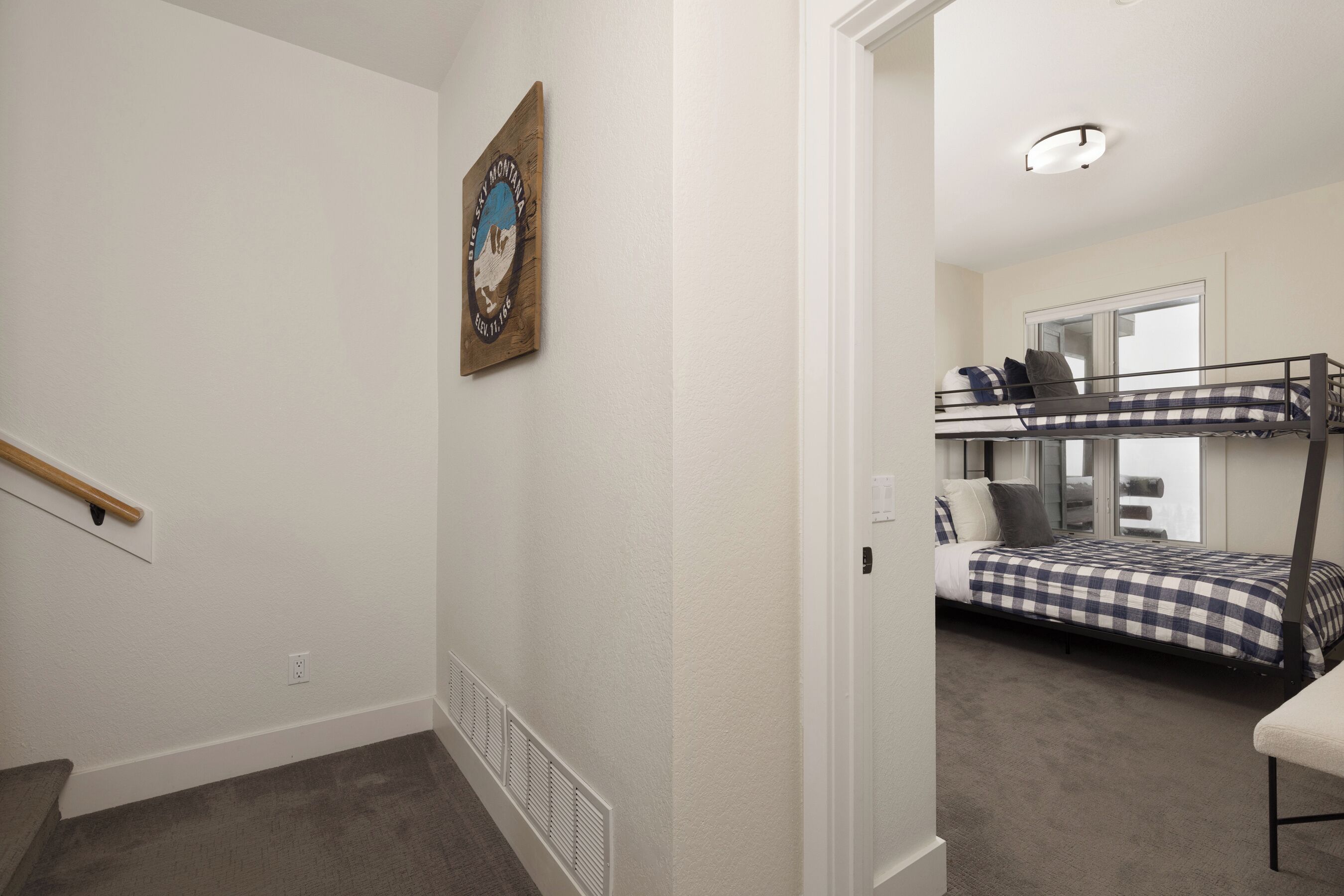 A room with a bunk bed, a small desk, and a window.