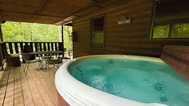 A hot tub on a wooden deck with a 'Welcome' sign above it.