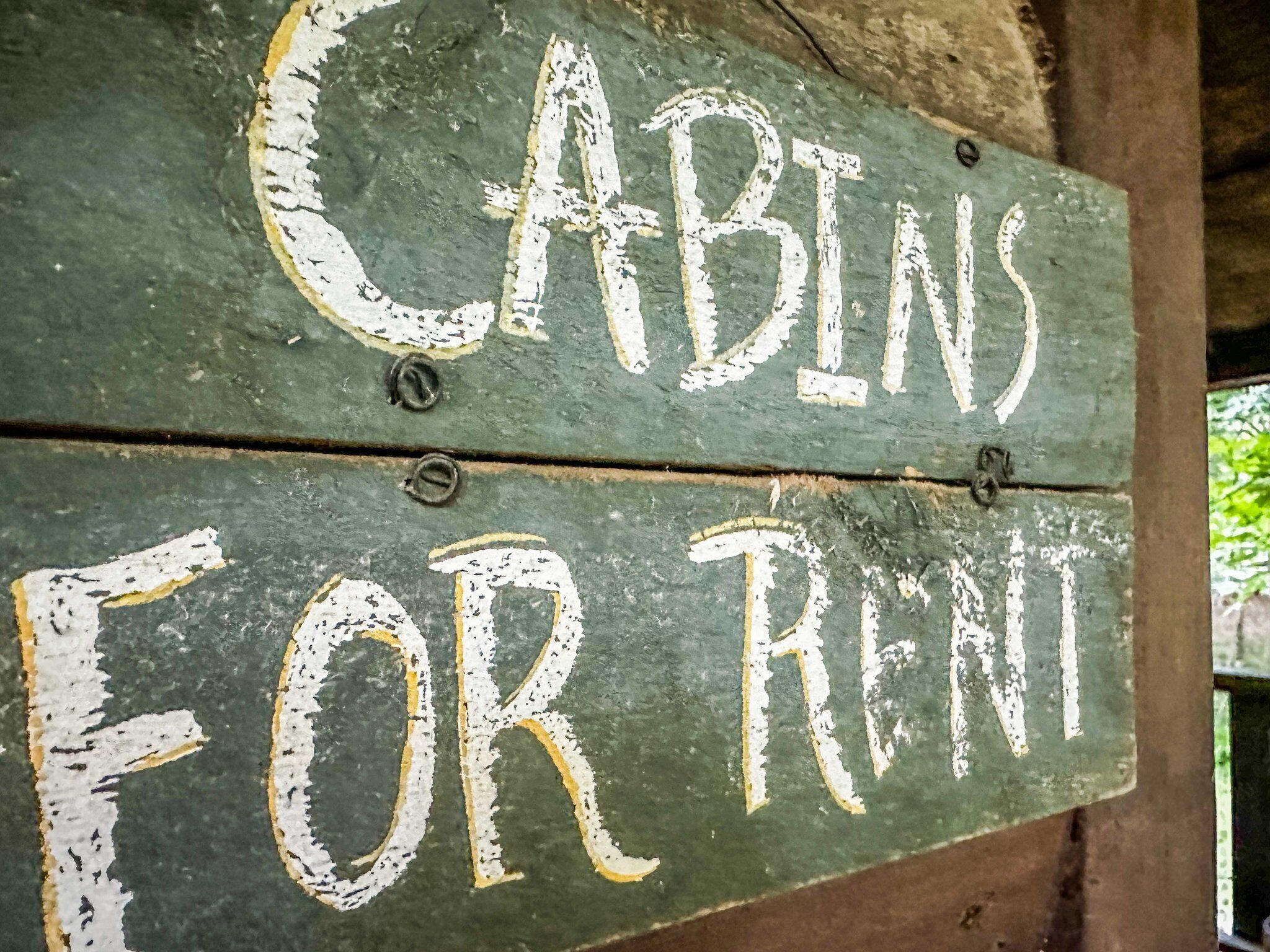 Un letrero de madera con la frase 'CABINS FOR RENT' pintada en blanco.