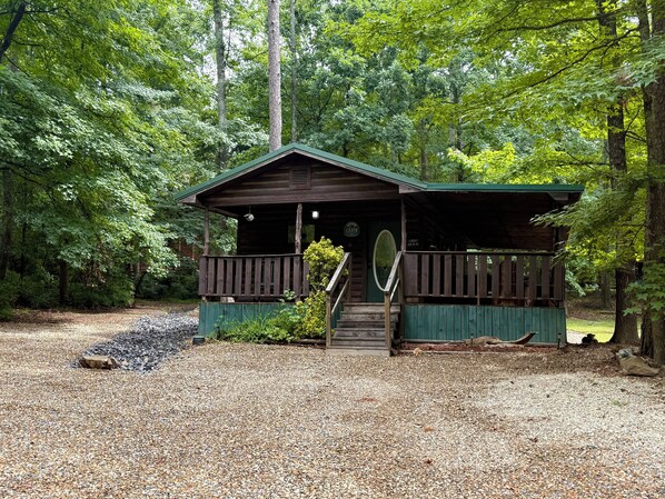 Un rustico chalet con una terrazza in legno, immerso in una fitta foresta.