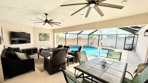 A spacious patio with a pool, outdoor furniture, and ceiling fans.