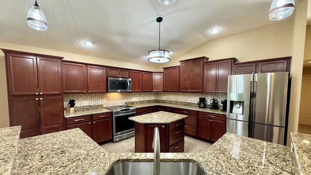 A kitchen with granite countertops, stainless steel appliances, and wooden cabinets.