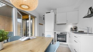A modern kitchen with white cabinets, a wooden dining table, and a built-in oven. - Awesome apartment in Slagelse with WiFi (Slagelse)